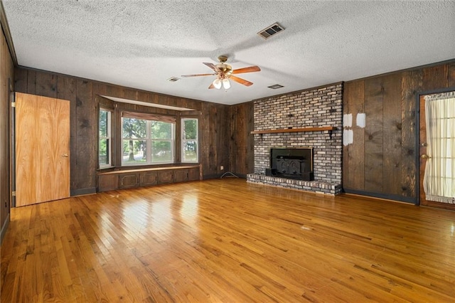 1113 4th Ave, Saraland, AL 36571 - unfurnished living room with a ceiling fan, wood-type flooring, wooden walls, a fireplace, and a textured ceiling
