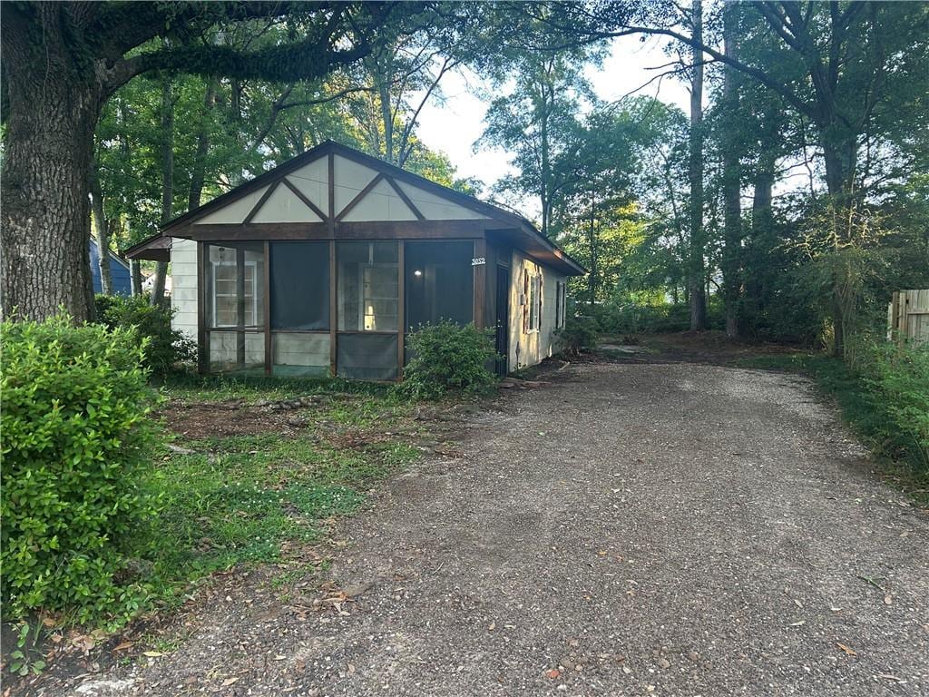 bungalow-style home featuring a sunroom and dirt driveway