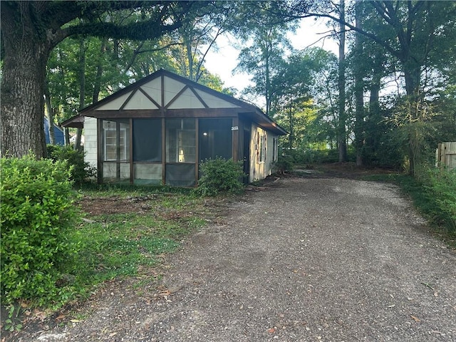 bungalow-style home featuring a sunroom and dirt driveway