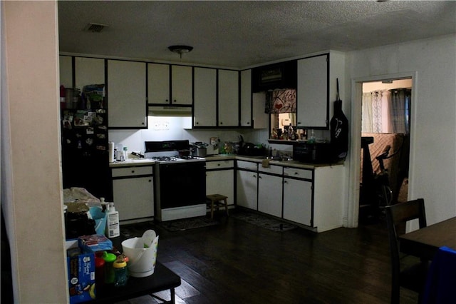 2517 Pinecliff Ct N, Mobile, AL 36605 - kitchen featuring gas range, freestanding refrigerator, under cabinet range hood, dark wood-style floors, and a textured ceiling