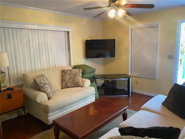 living room featuring dark wood-type flooring, ceiling fan, ornamental molding, and a healthy amount of sunlight