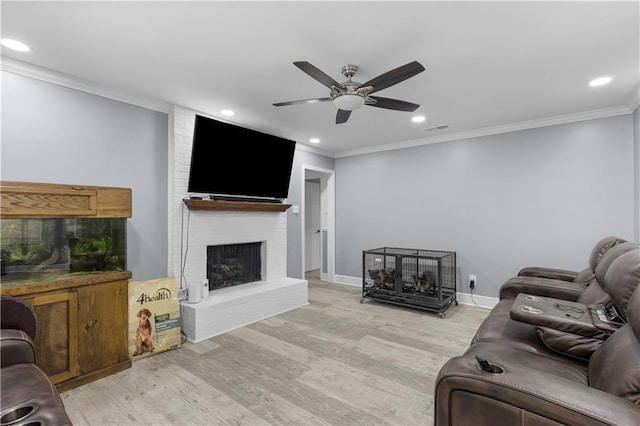 living room with visible vents, light wood-style flooring, ceiling fan, crown molding, and a brick fireplace