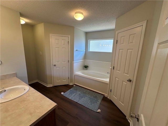 bathroom with a washtub, vanity, hardwood / wood-style flooring, and a textured ceiling