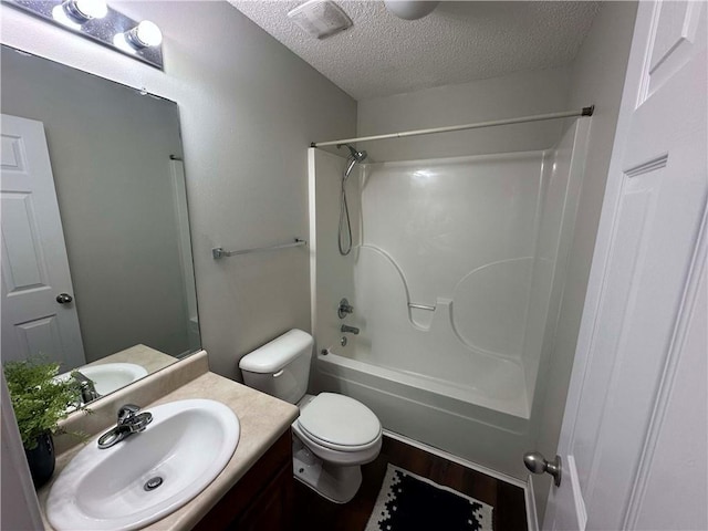 full bathroom with tub / shower combination, vanity, wood-type flooring, a textured ceiling, and toilet