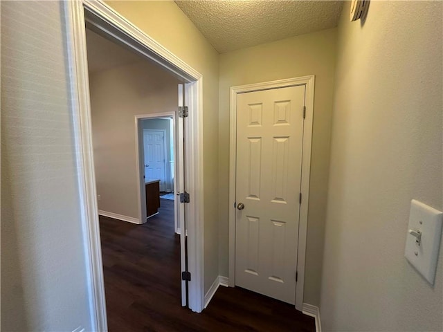 hall with dark hardwood / wood-style floors and a textured ceiling