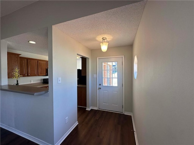 entryway with dark wood-type flooring and a textured ceiling