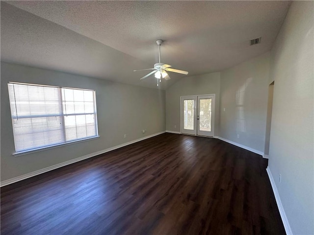 spare room with vaulted ceiling, dark hardwood / wood-style flooring, ceiling fan, a textured ceiling, and french doors