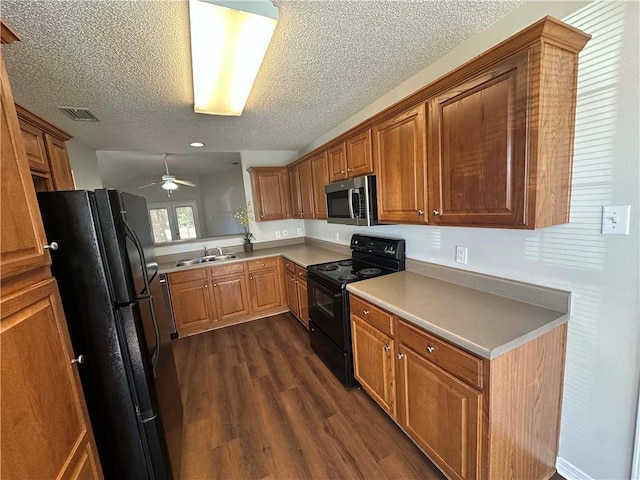 kitchen featuring sink, ceiling fan, black appliances, dark wood-type flooring, and a textured ceiling