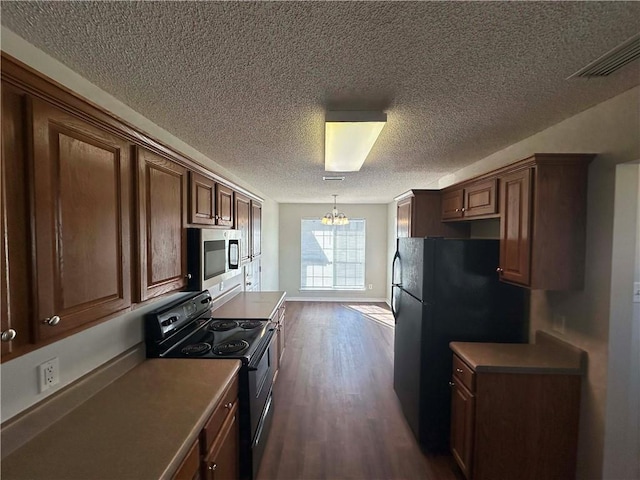 kitchen featuring dark hardwood / wood-style floors, a chandelier, hanging light fixtures, black appliances, and a textured ceiling