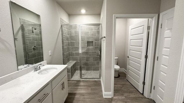 bathroom featuring an enclosed shower, vanity, toilet, and wood-type flooring