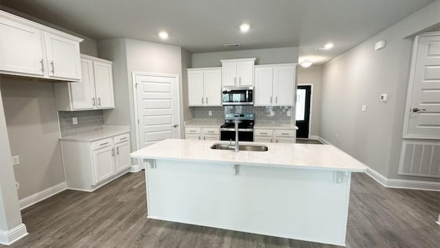 kitchen with an island with sink, dark wood-type flooring, white cabinets, and stainless steel appliances