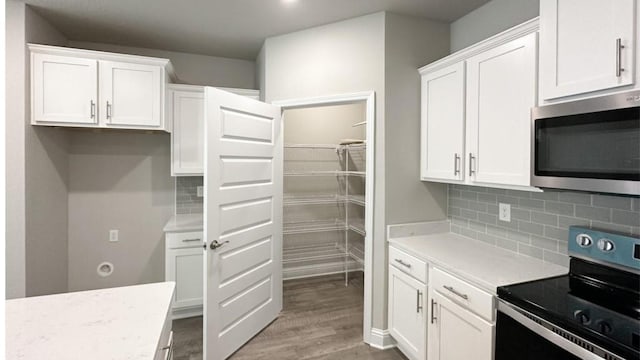 kitchen featuring electric range, light hardwood / wood-style floors, white cabinets, and tasteful backsplash