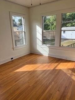 spare room with a healthy amount of sunlight and hardwood / wood-style floors