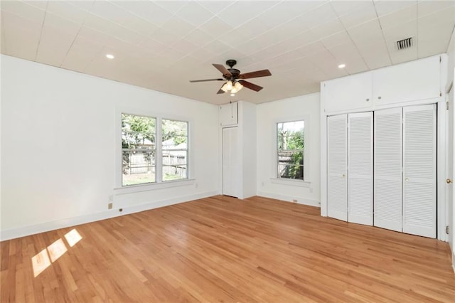 unfurnished bedroom with multiple windows, wood-type flooring, and ceiling fan