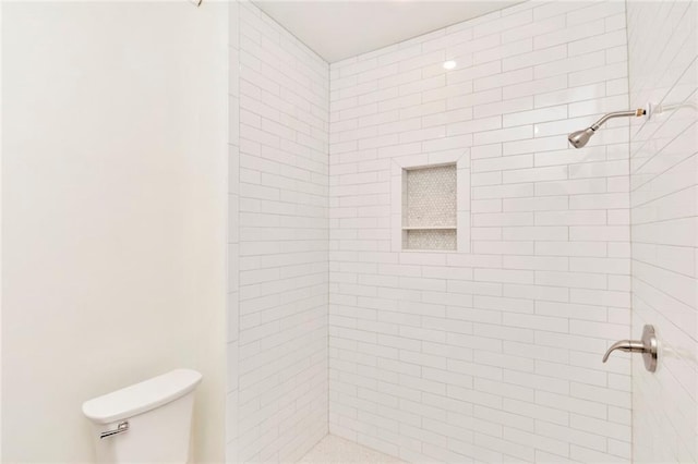 bathroom featuring toilet and a tile shower