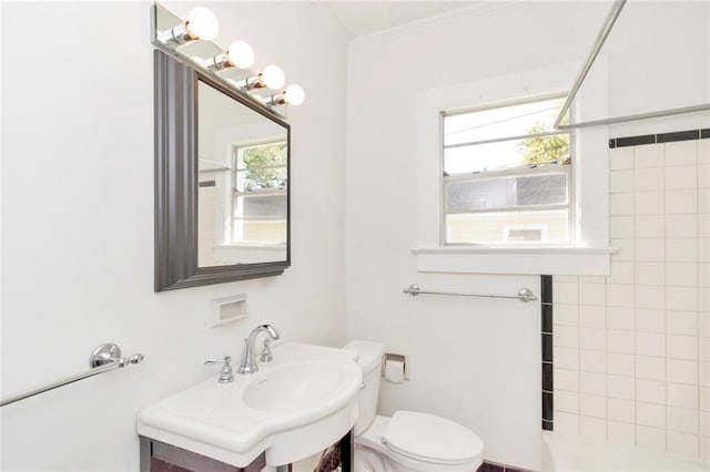 bathroom featuring toilet, a wealth of natural light, and tiled shower