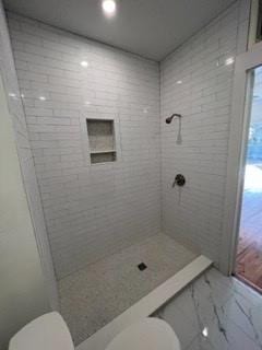 bathroom with tiled shower and toilet