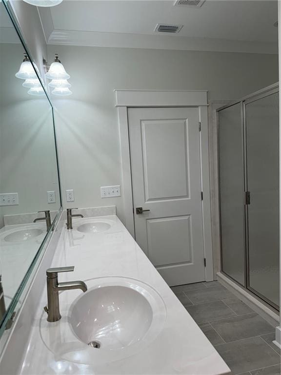 bathroom featuring tile flooring, double sink vanity, ornamental molding, and a shower with door