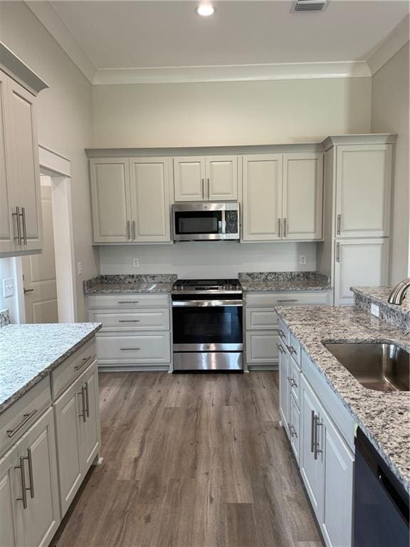 kitchen with sink, hardwood / wood-style flooring, ornamental molding, and stainless steel appliances