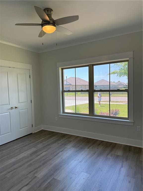 spare room featuring a healthy amount of sunlight, crown molding, dark hardwood / wood-style floors, and ceiling fan