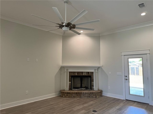 unfurnished living room with crown molding, ceiling fan, hardwood / wood-style floors, and a brick fireplace