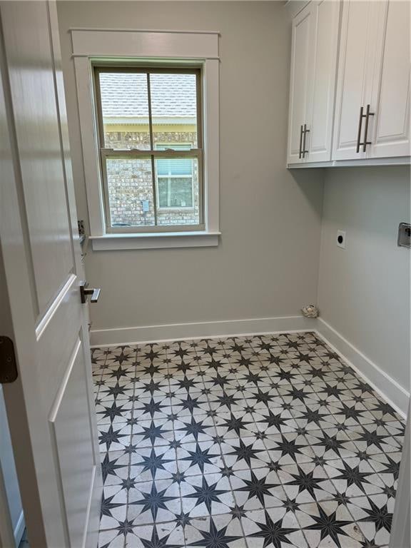 clothes washing area with light tile flooring, electric dryer hookup, and cabinets