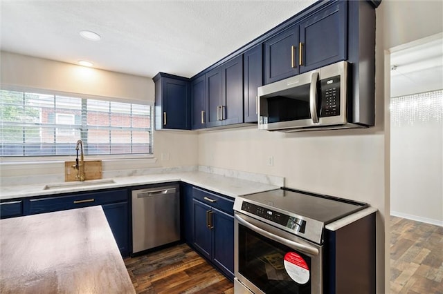 kitchen featuring blue cabinets, appliances with stainless steel finishes, sink, and dark wood-type flooring