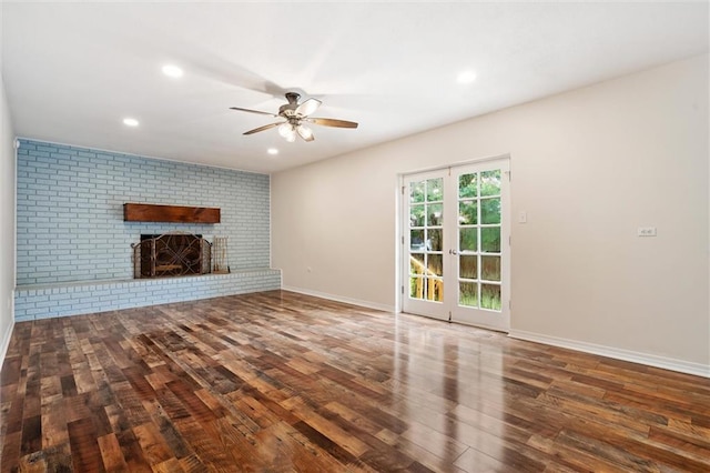 unfurnished living room with a brick fireplace, dark hardwood / wood-style floors, ceiling fan, and french doors