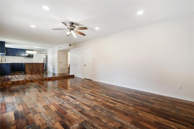 unfurnished living room featuring sink, dark wood-type flooring, and ceiling fan