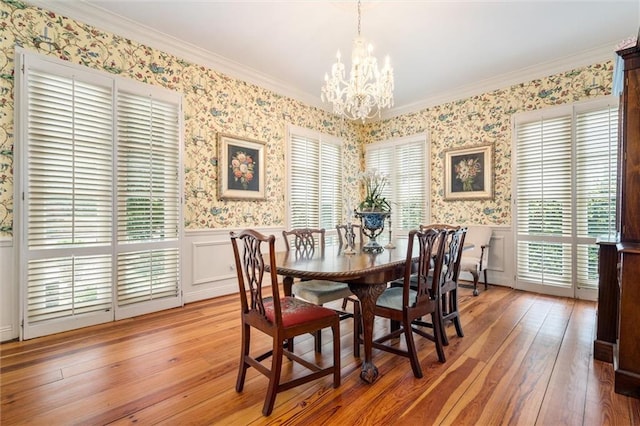 dining space with crown molding, a notable chandelier, and light hardwood / wood-style flooring