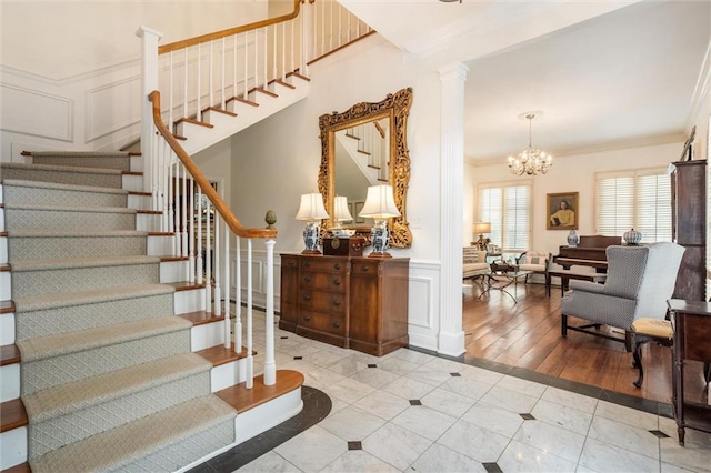 interior space featuring decorative columns, hardwood / wood-style flooring, a notable chandelier, and ornamental molding