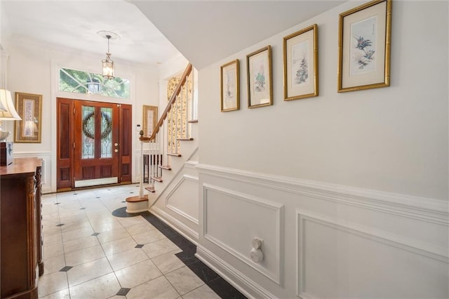 foyer entrance featuring a chandelier, ornamental molding, and light tile patterned floors