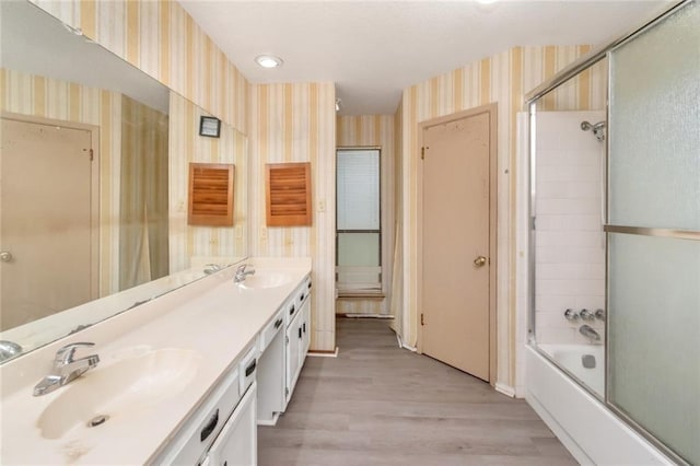 6500 Camden Cir, Mobile, AL 36618 - full bath featuring wallpapered walls, wood finished floors, double vanity, and combined bath / shower with glass door