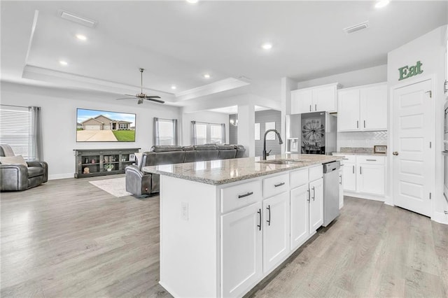kitchen featuring a sink, a raised ceiling, stainless steel dishwasher, open floor plan, and recessed lighting