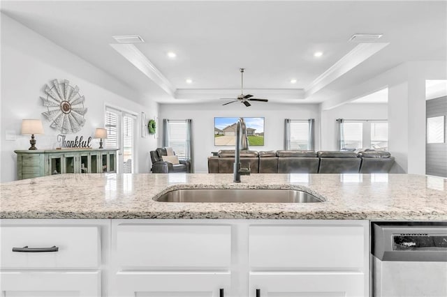 kitchen with a sink, dishwasher, open floor plan, a tray ceiling, and ornamental molding