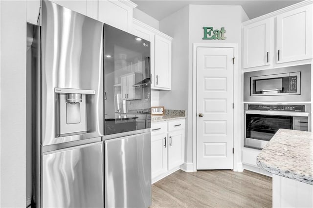kitchen featuring stainless steel appliances, light wood finished floors, white cabinetry, and light stone counters