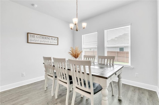 dining space featuring a chandelier, wood finished floors, and baseboards