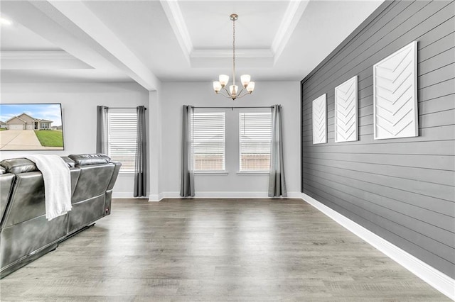 dining area featuring a raised ceiling, a chandelier, wooden walls, wood finished floors, and crown molding