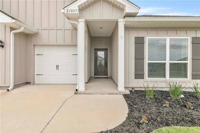 view of exterior entry with board and batten siding, concrete driveway, and an attached garage