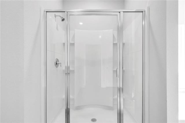 full bath with a shower stall and a textured wall