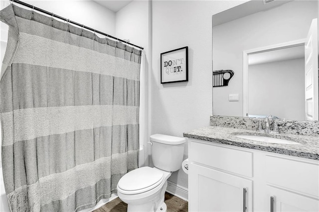 bathroom with toilet, wood finished floors, vanity, and baseboards