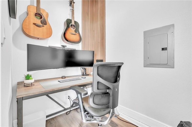 home office with electric panel, wood finished floors, and baseboards
