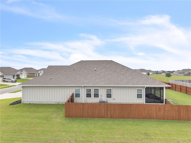back of property with roof with shingles, a sunroom, and a residential view