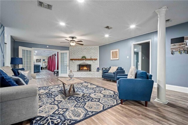 2017 Knollwood Dr, Mobile, AL 36609 - living room featuring a ceiling fan, wood finished floors, a textured ceiling, ornate columns, and a fireplace