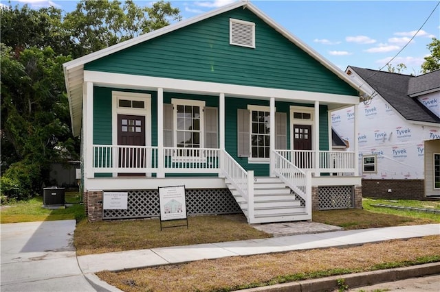 view of front of house featuring cooling unit, covered porch, and a front yard