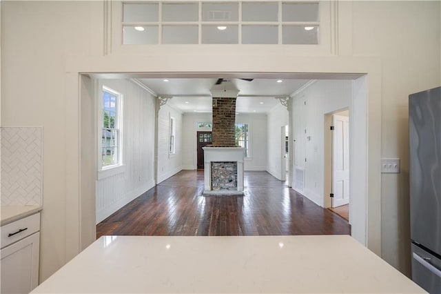 kitchen featuring white cabinetry, decorative columns, stainless steel refrigerator, and a healthy amount of sunlight