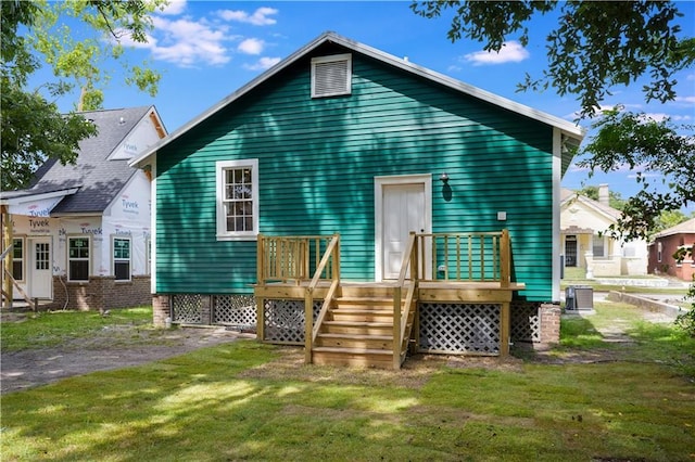 rear view of property featuring central AC and a lawn