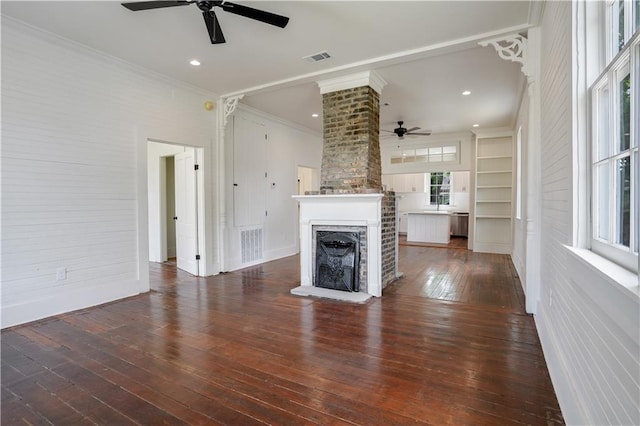 unfurnished living room with ornate columns, crown molding, dark wood-type flooring, and ceiling fan