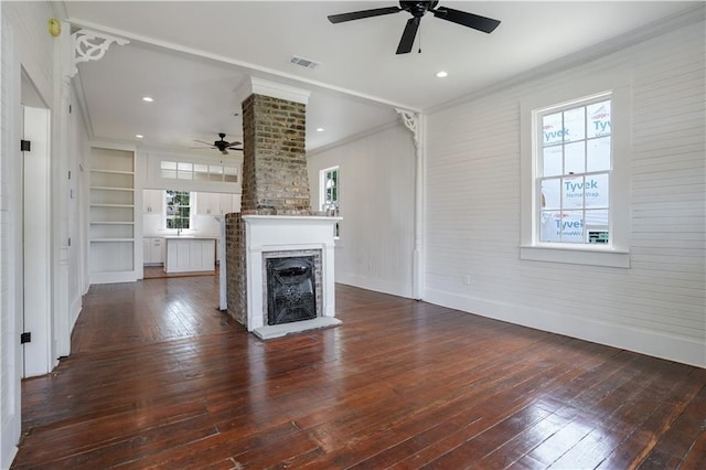 unfurnished living room featuring crown molding, dark wood-type flooring, built in features, and a fireplace