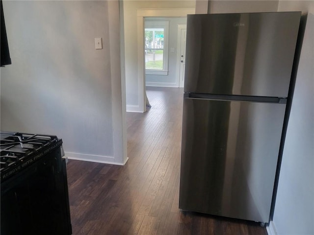 kitchen with stainless steel refrigerator, black stove, and dark hardwood / wood-style flooring